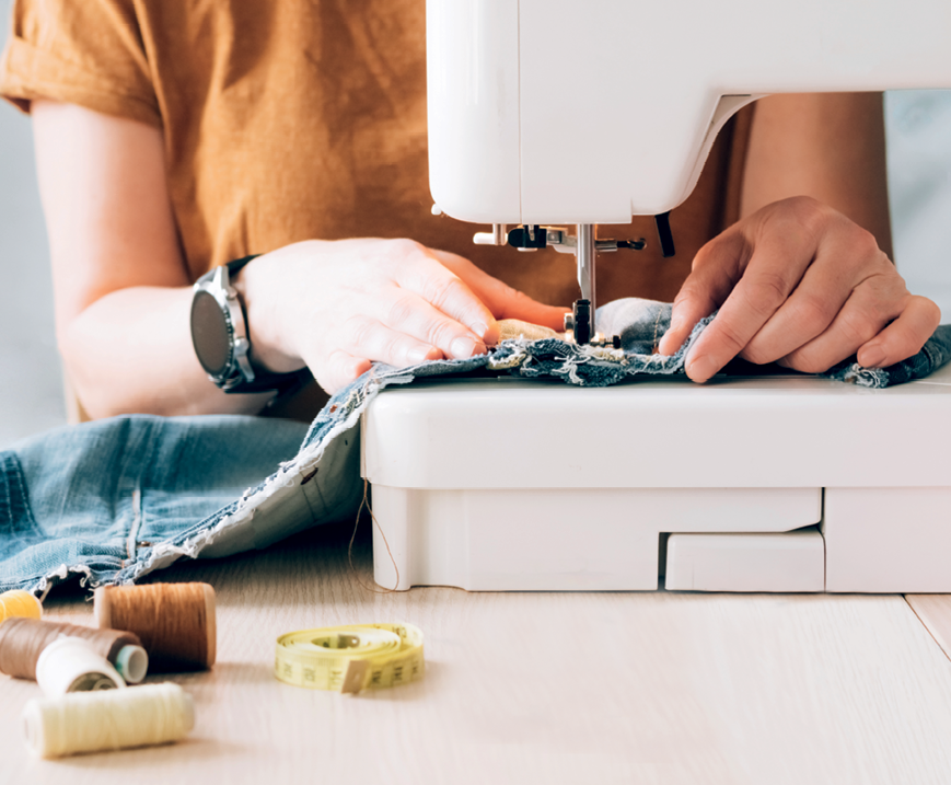 A person repairing denim with a sewing machine